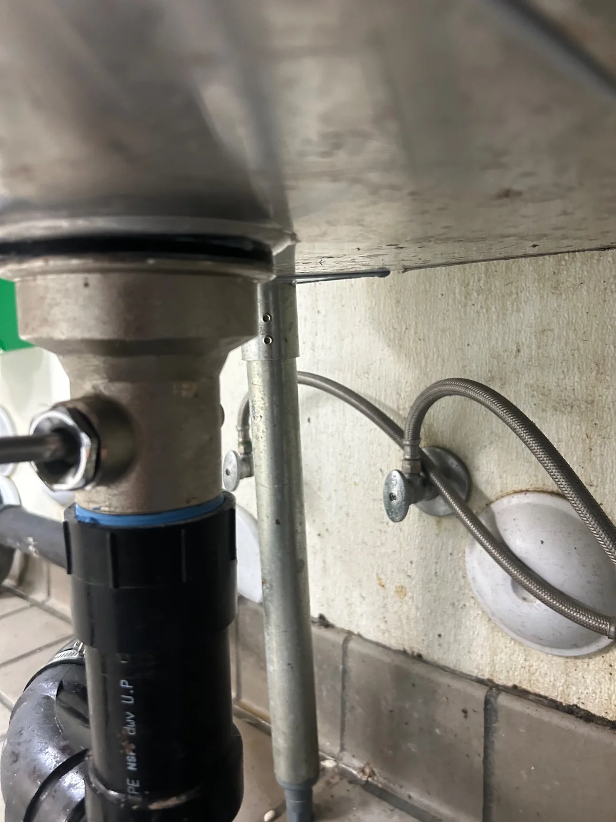 Sink drain body, black gasket and pipe below the stainless-steel basin