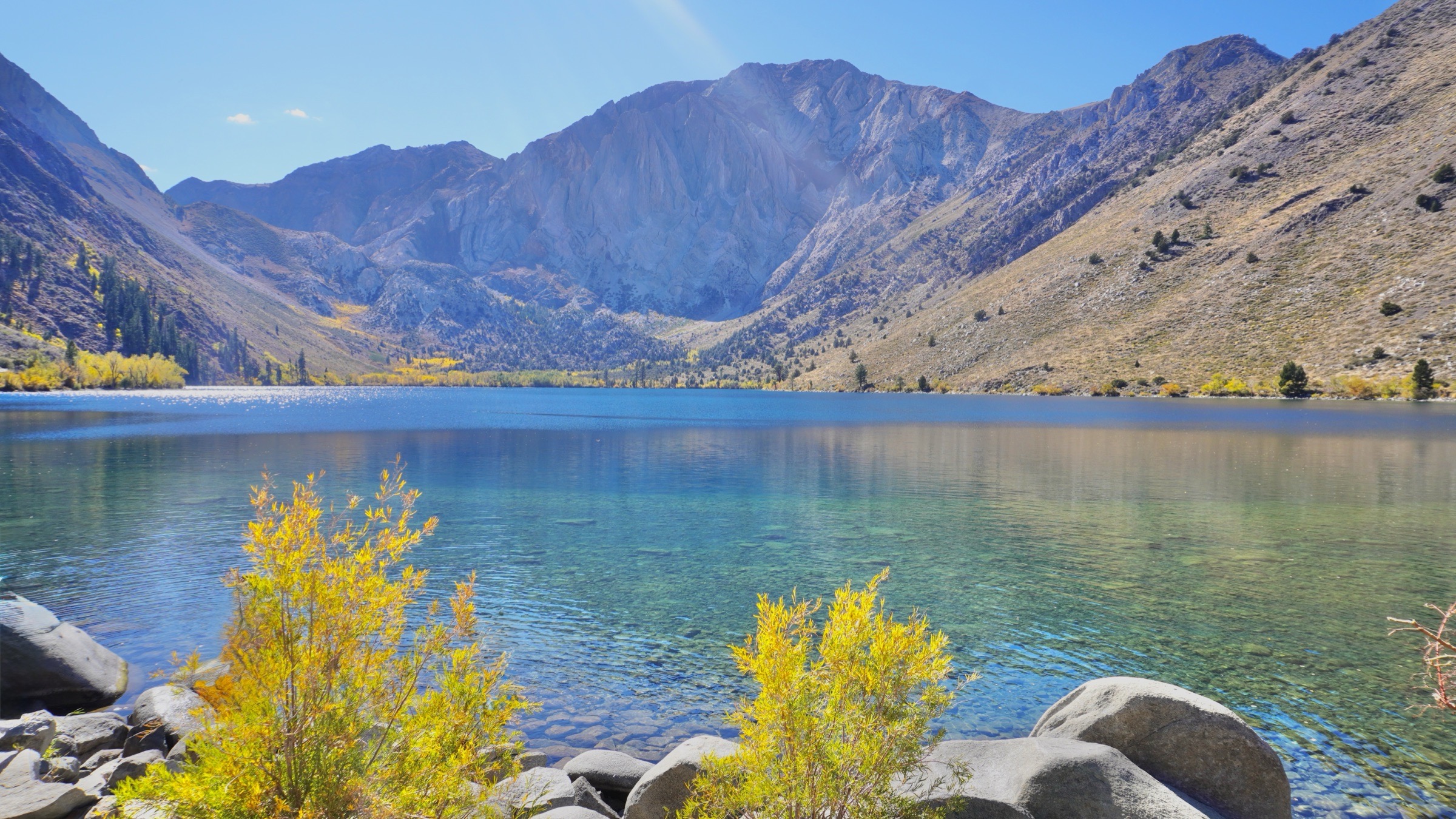 Clear blue water, rocky mountains, and golden fall foliage at Convict Lake in the Eastern Sierra