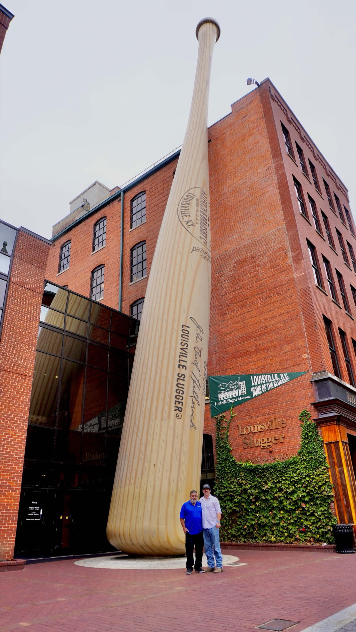 Tim Yslava and his father standing beneath the giant baseball bat outside the Louisville Slugger Museum and Factory