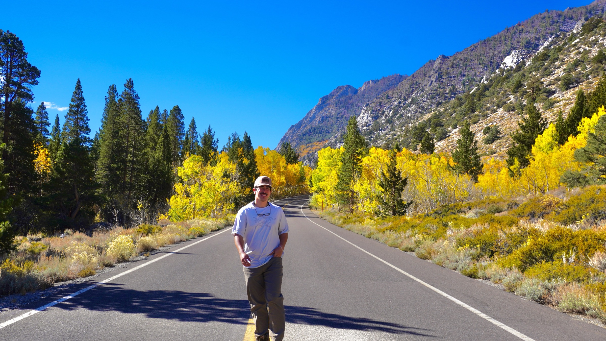 Tim Yslava standing on a road surrounded by yellow fall foliage and Sierra mountains near Mammoth Lakes